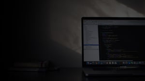 Ноутбук на столі, оточений темним фоном, що створює атмосферу зосередженості
