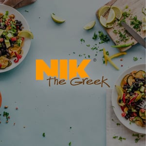 Gedeckter Tisch mit zwei Bowls mit griechischen Spezialitäten, im Vordergrund ist das Logo von Nik the Greek zu sehen.