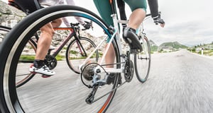 Two people ride along a road on bicycles.
